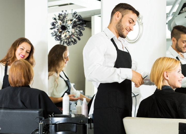 Male and female hairdressers doing hair