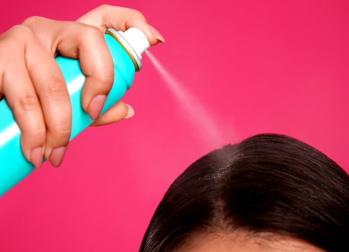 Woman applying dry shampoo to the roots of her hair