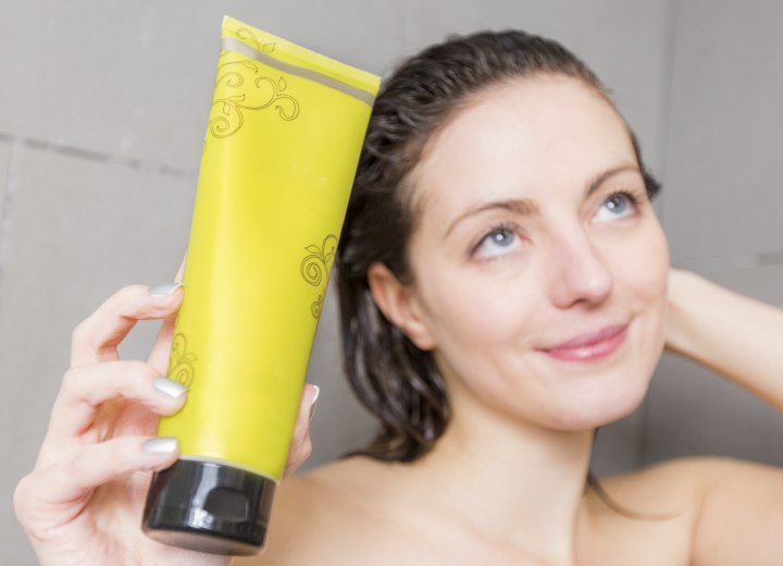 Brunette with wet hair and a tube of shampoo