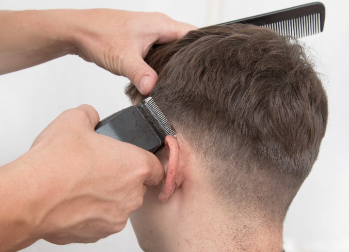 Stylist while fading hair with clippers