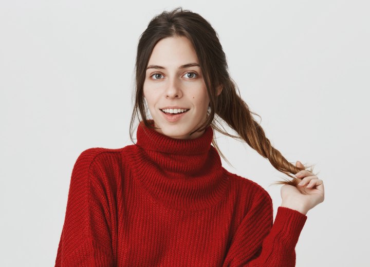 Woman wearing a red turtleneck and pulling her own hair