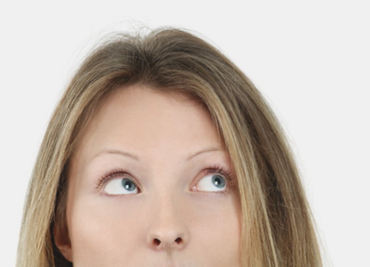 Woman looking up to check her hair for thinning