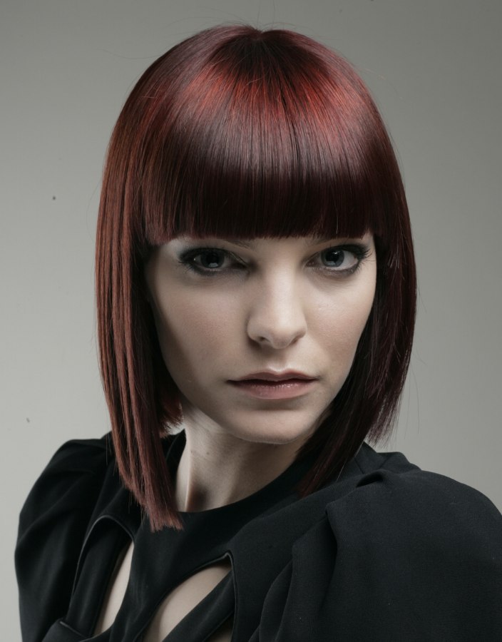 Trendy bob hairstyle with a red hue and over the brows bangs