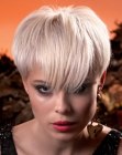 Platinum blonde pixie cut with extreme short sides and plunging bangs