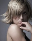 Short blonde razor-cut hair styled with an outward bend