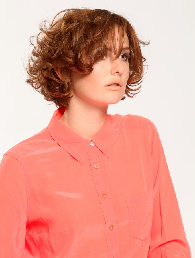 Short curly hairstyle with layers and a silk blouse with a 