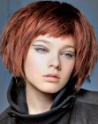 Red hair cut into a bob with short bangs and jagged cutting lines