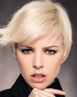 Blonde pixie cut with lifted bangs and an outward curve