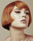Short bob with wispy bangs and an intense red hair color