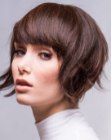 Short feminine hairstyle with wispy sides and full long bangs