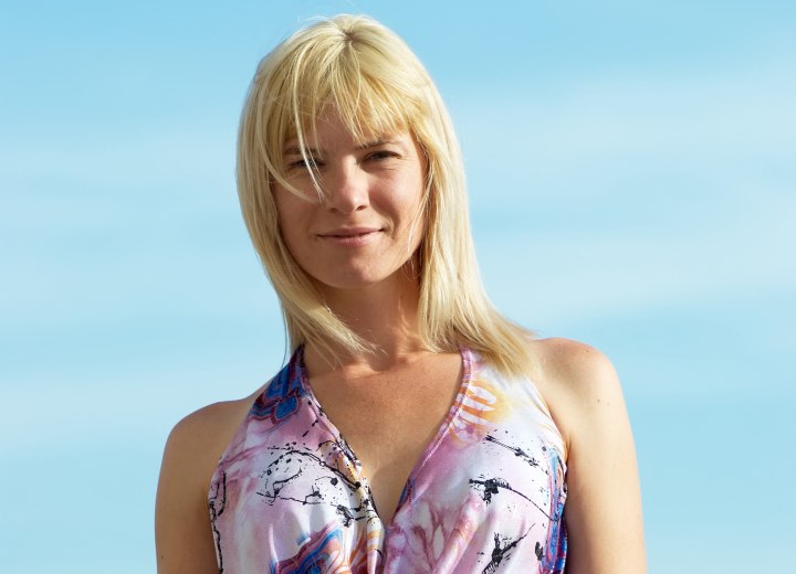 Woman with shoulder-length blonde hair and bangs