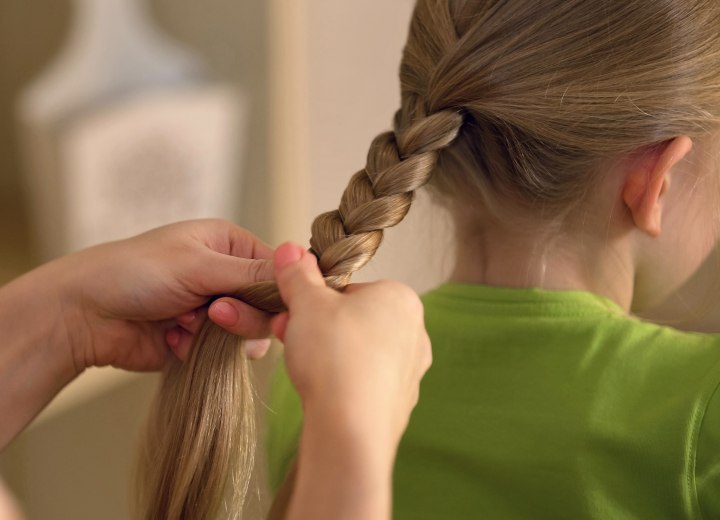 A mother who is braiding her daughter's hair