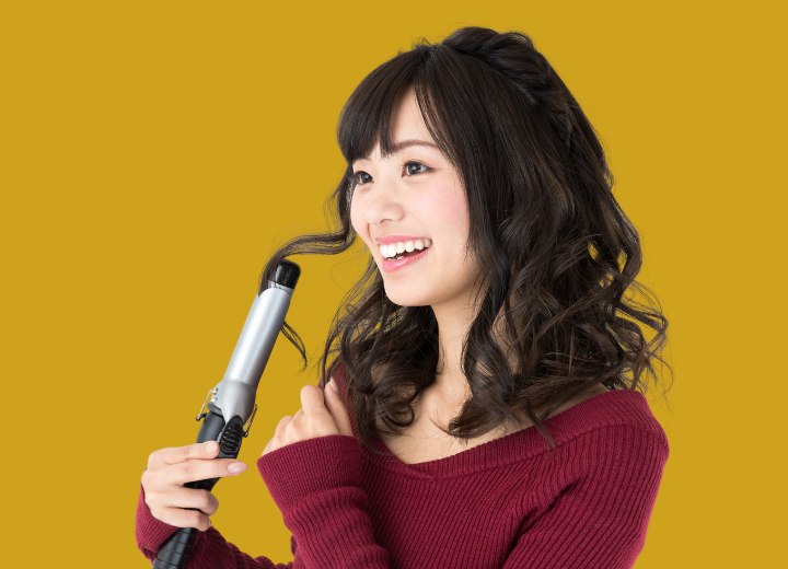 Asian woman curling her hair with a curling iron