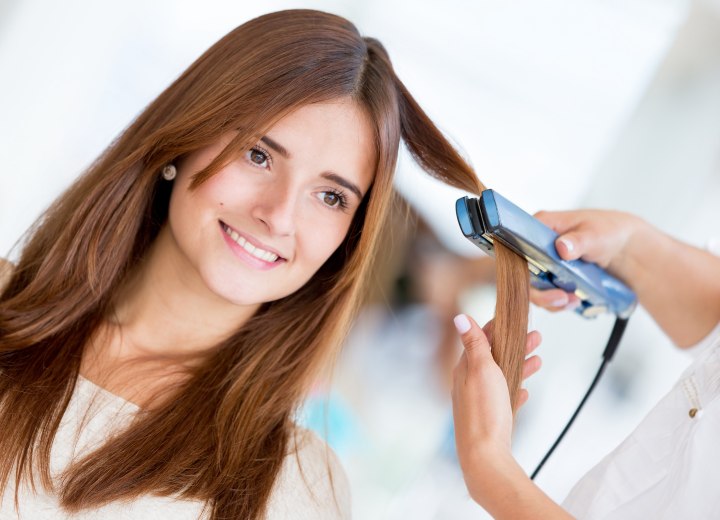 Stylist straightening hair with a flat iron