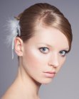 Simple chignon with smooth styling and a feathery hair accessory