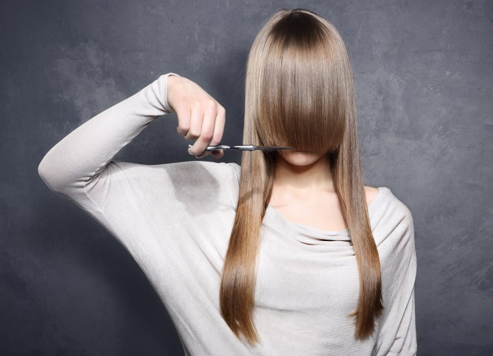 Woman with long hair cutting her own fringe