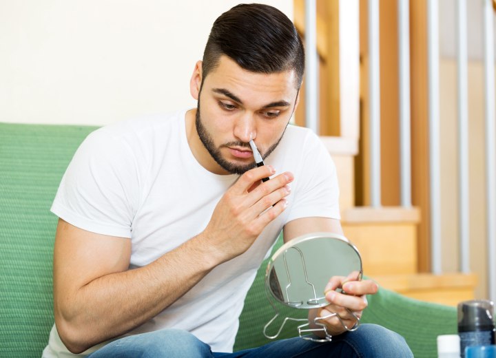 Man who is removing his nose hair