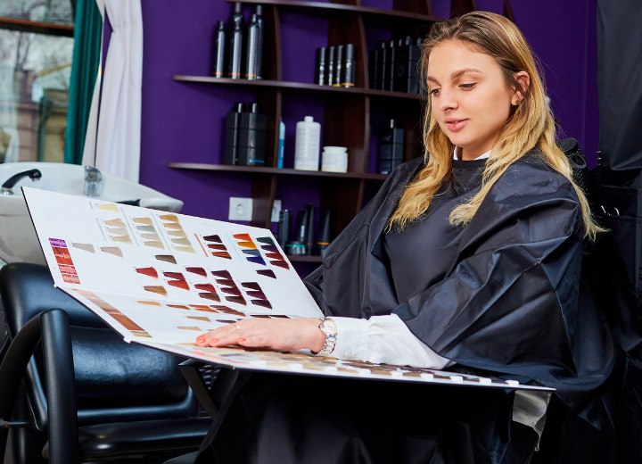 Caped woman with long hair who is choosing a new hair color